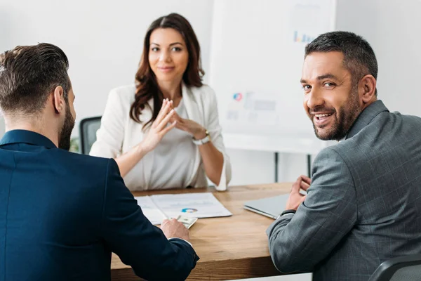 Focus selettivo degli investitori in giacca e cravatta che parlano con un consulente attraente nello spazio di lavoro — Foto stock