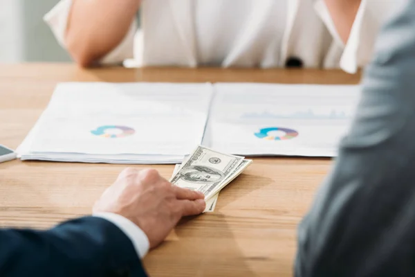 Foyer sélectif de l'homme tenant des billets en dollars avec une femme sur fond — Photo de stock