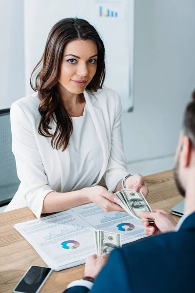 Selective focus of attractive advisor taking money from investor at office — Stock Photo