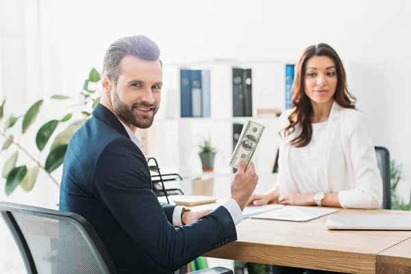 Selective focus of investor holding dollar banknotes and advisor looking at it — Stock Photo