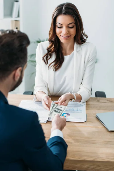 Selective focus of beautiful advisor taking money from investor at office — Stock Photo