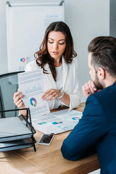 Selective focus of beautiful advisor and investor in suits discussing document at workplace — Stock Photo