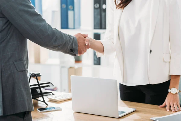 Partial view of woman and man shaking hands at office — Stock Photo