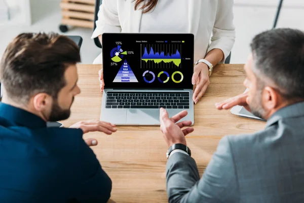 Enfoque selectivo de asesor mostrando a los inversores portátil con la tasa de sitio web en la pantalla en el lugar de trabajo - foto de stock