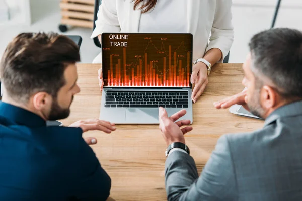 Selective focus of advisor showing to investors laptop with online trade website on screen at workplace — Stock Photo