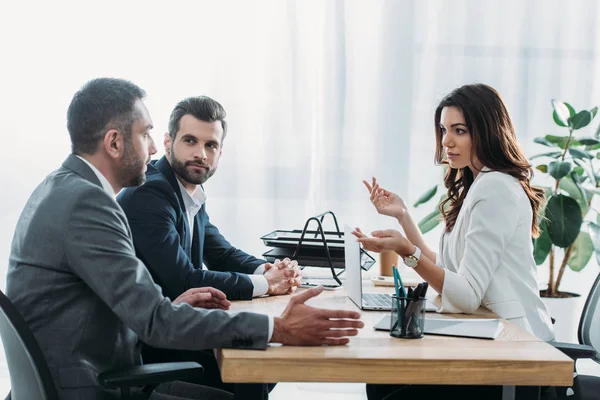 Beautiful advisor and investors in suits talking at workplace — Stock Photo