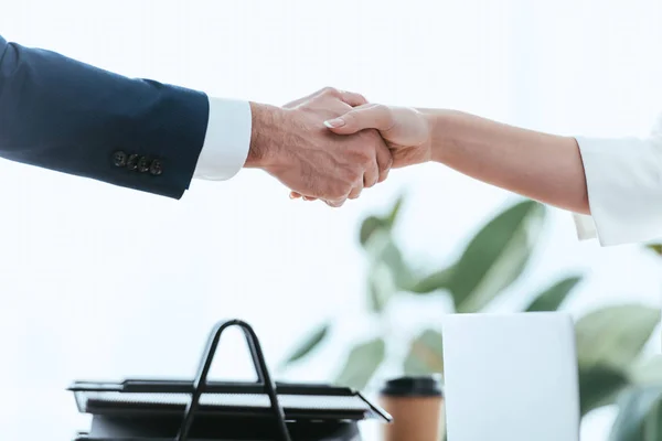 Selective focus of woman and man shaking hands at office — Stock Photo