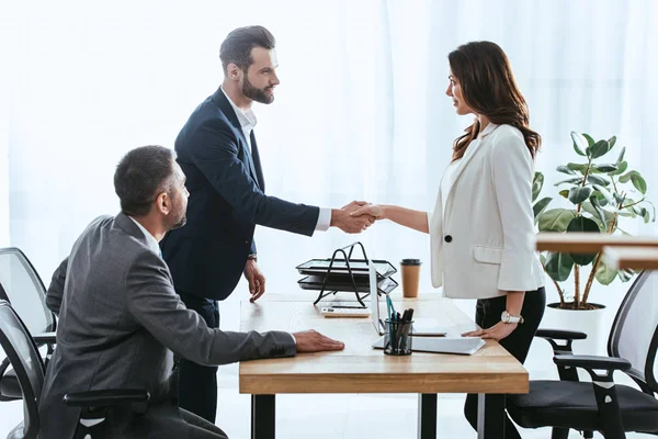 Schöne Beraterin und Anlegerin im Anzug beim Händeschütteln im Büro — Stockfoto