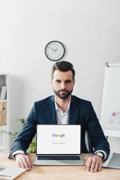 Schöner Berater im Anzug zeigt Laptop mit Google-Website auf dem Bildschirm — Stockfoto