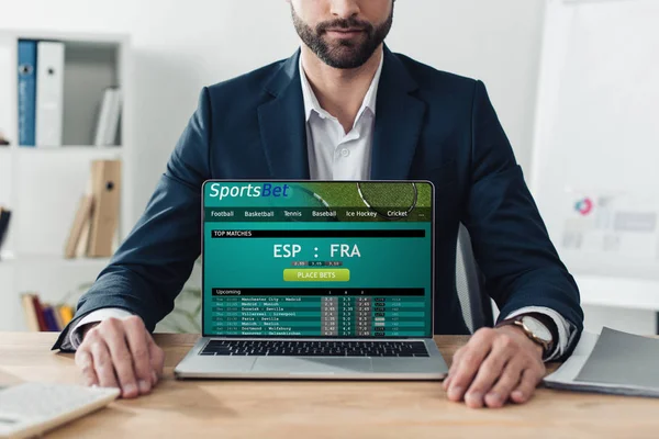 Vista ritagliata del consulente in giacca e cravatta che mostra il computer portatile con il sito web sportsbet sullo schermo in ufficio — Foto stock