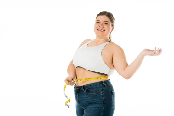 Усміхнена жінка з надмірною вагою вимірює талію з вимірювальною стрічкою ізольовано на білому, концепція позитиву тіла — стокове фото