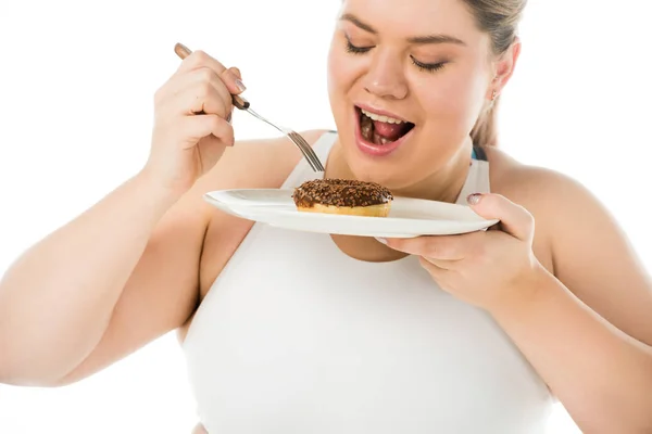Overweight woman eating sweet doughnut from plate isolated on white, body positivity concept — Stock Photo