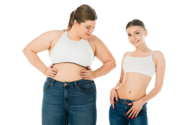 Schlanke und übergewichtige Frauen in Jeans posieren gemeinsam isoliert auf weißem, Body-Positivity-Konzept — Stockfoto