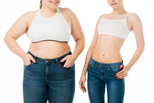 Abgeschnittene Ansicht von lächelnden schlanken und übergewichtigen Frauen in Jeans, die zusammen isoliert auf weißem, Body-Positivity-Konzept posieren — Stockfoto