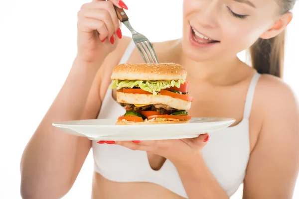 Gros plan de belle femme en sous-vêtements manger hamburger savoureux avec fourchette de la plaque isolée sur blanc — Photo de stock