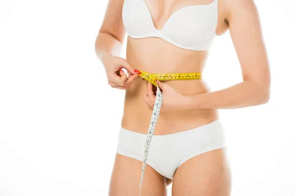 Cropped view of slim woman in underwear measuring waist with centimeter isolated on white — Stock Photo