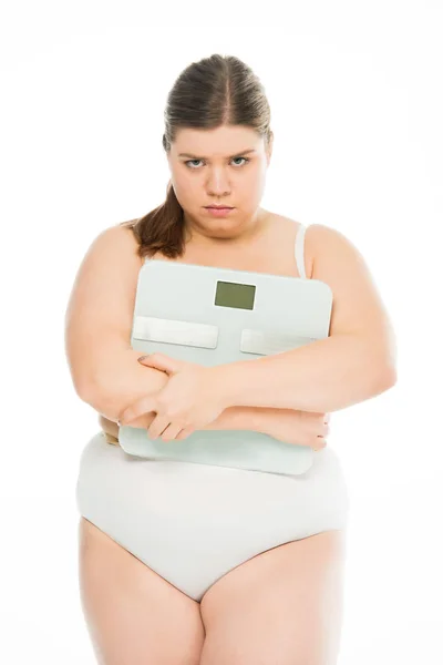 Molesto joven mujer con sobrepeso sosteniendo escamas aisladas en blanco, perder peso concepto - foto de stock