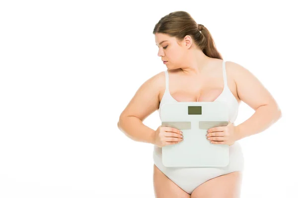 Upset young overweight woman in underwear holding scales and looking away isolated on white, lose weight concept — Stock Photo