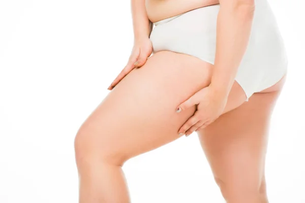 Vue recadrée de la femme en surpoids posant avec les mains sur la jambe isolée sur blanc, concept de positivité du corps — Photo de stock