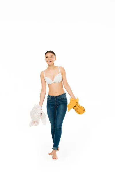 Slim woman in underwear and blue jeans holding blouses isolated on white — Stock Photo