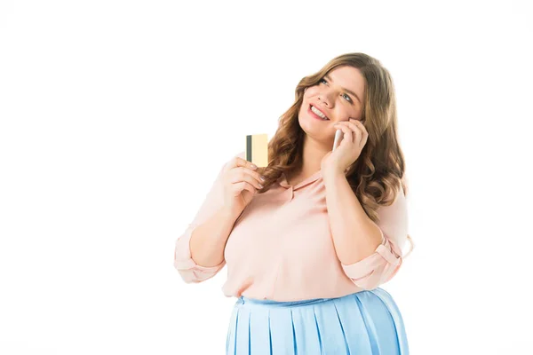 Feliz elegante plus size mulher falando no smartphone e segurando cartão de crédito isolado no branco — Fotografia de Stock