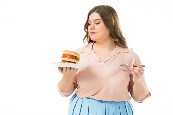 Attractive overweight woman looking at tasty burger on plate isolated on white — Stock Photo