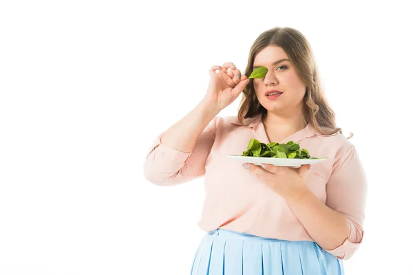 Beautiful overweight woman holding fresh green spinach leaf near eye isolated on white — Stock Photo