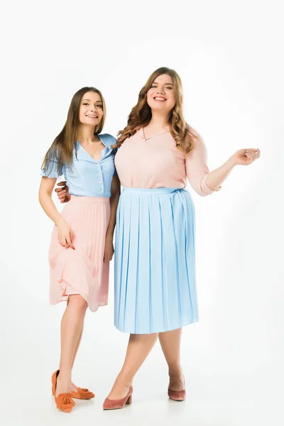 Smiling elegant overweight and slim women embracing on white background — Stock Photo