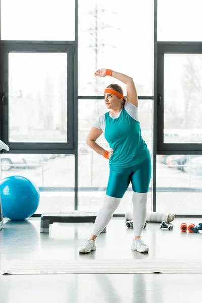 Übergewichtige Frau trainiert in Sportbekleidung in der Nähe von Fitnessball — Stockfoto