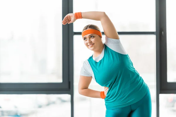 Mujer alegre con sobrepeso haciendo ejercicio en ropa deportiva - foto de stock