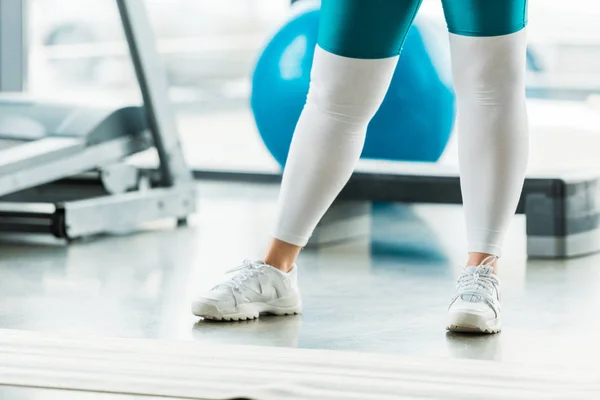 Vista recortada de la mujer con sobrepeso de pie en el gimnasio - foto de stock