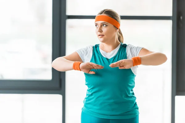 Attractive overweight woman exercising in sportswear in gym — Stock Photo