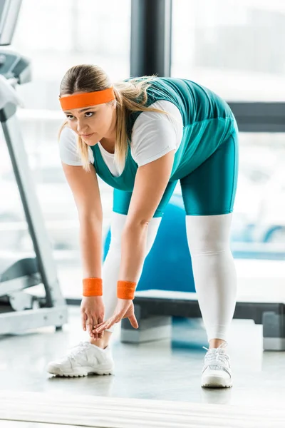 Focused overweight woman stretching near fitness mat in gym — Stock Photo