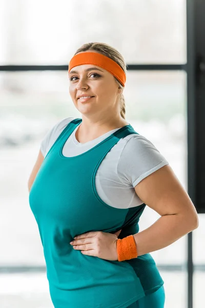 Alegre mujer con sobrepeso sonriendo mientras posando en el gimnasio - foto de stock