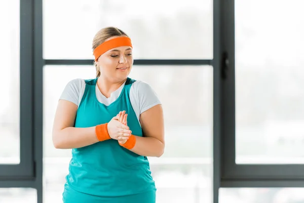 Mujer con sobrepeso de pie en ropa deportiva y manos de calentamiento - foto de stock