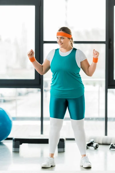 Улыбающаяся толстая женщина тренируется в спортивной одежде в спортзале — стоковое фото