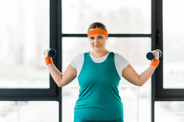 Cheerful overweight woman workouting in sportswear with dumbbells — Stock Photo