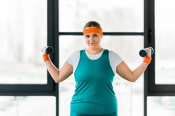 Mulher com sobrepeso alegre trabalhando em sportswear com halteres — Fotografia de Stock