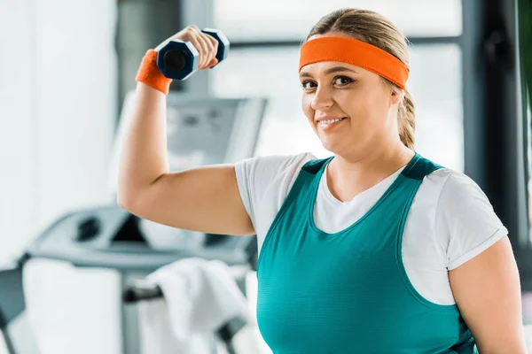 Happy overweight woman workouting in sportswear with dumbbell — Stock Photo
