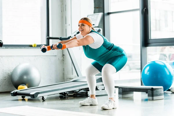 Alegre más entrenamiento de mujer de tamaño con pesas alfombra de fitness aseado - foto de stock