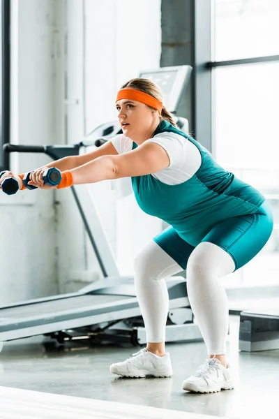 Confident plus size woman training with dumbbells neat fitness mat — Stock Photo