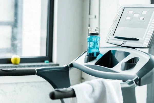 Selective focus of bottle with drink near treadmill in gym — Stock Photo