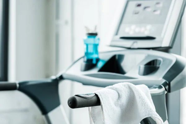 Selective focus of white towel hanging on modern treadmill in gym — Stock Photo