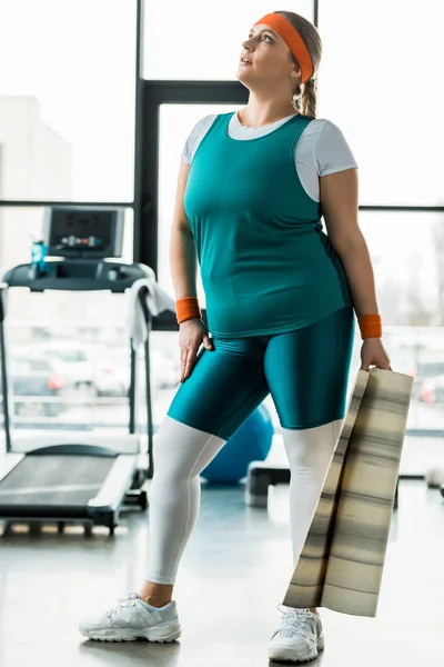 Attraktive übergewichtige Frau hält Fitnessmatte im Fitnessstudio — Stockfoto