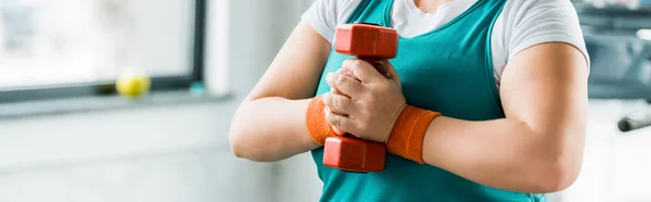 Cropped view of overweight girl holding dumbbell in gym — Stock Photo