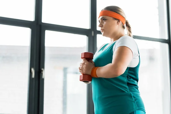 Confiance fille en surpoids tenant haltère dans la salle de gym — Photo de stock