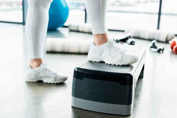 Cropped view of plus size girl standing on step platform in gym — Stock Photo