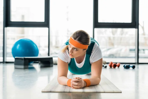 Menina com sobrepeso fazendo exercício prancha no tapete de fitness — Fotografia de Stock