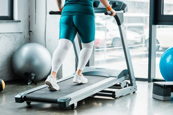 Vue recadrée de la fille en surpoids courir sur tapis roulant dans la salle de gym — Photo de stock