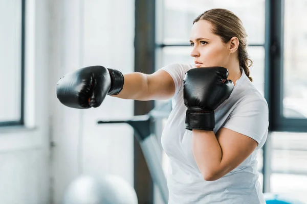Confiado chica con sobrepeso practicando kickboxing en el gimnasio - foto de stock